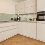 Moderne Küche mit weißen Schränken, Glasrückwand und integriertem Ofen.