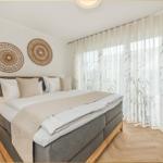 Schlafzimmer mit Bett, Nachttisch und Fenster mit Vorhängen.