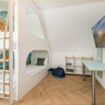 Kinderzimmer mit Kletterturm, Bett und Schreibtisch an der Wand.