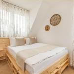 Schlafzimmer mit Holzbett, Fenster mit Vorhängen und Wanddekoration.