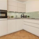 Moderne Küche mit hellen Schränken, Edelstahlgeräten und Holzboden.