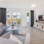 Wohnzimmer mit Sofa, Couch, Fernseher und Terrasse mit Blick.