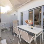 Terrasse mit Tisch, Stühlen und Sonnenschutz. Durchgang zur Küche sichtbar.