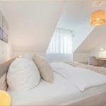 Schlafzimmer mit Dachschrägen, Bett, Schreibtisch und Lampe.