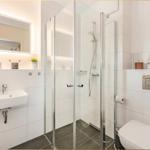 Badezimmer mit Dusche, Waschbecken und Toilette. Dekoration: Segelbootmodell.