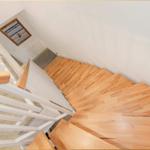 Holztreppe mit weißem Geländer führt nach oben. Wandbild mit Strandmotiv über dem Treppenhaus.