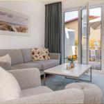 Wohnzimmer mit Sofa, Couchtisch und Blick auf Balkon mit Sonnenschirm.