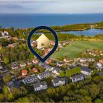 Luftbild einer Wohngegend mit Wald, Feldern und Blick aufs Meer.