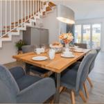 Essbereich mit Holztisch, grauen Stühlen und Blick auf Balkon.