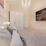 Schlafzimmer mit Bett, Kleiderschrank und Wandbild. Deckenleuchte und Wandlampe.