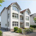 Weiße Villa mit Balkon und gepflegtem Gartenbereich