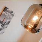 Eine hängende Lampe mit Glasgehäuse und eine Wanddekoration mit schwarz-weißem Motiv.