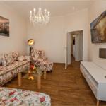 Wohnzimmer mit Sofa, Sessel und Fernseher an der Wand.