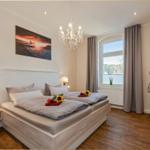 Schlafzimmer mit Doppelbett, Fenster, TV und Kronleuchter.