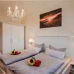 Schlafzimmer mit Doppelbett, Kleiderschrank und Wandbild. Deckenleuchte und Nachttische.