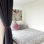 Schlafzimmer mit Bett, Kissen und Wandbild. Dunkle Vorhänge sind teilweise zugezogen.