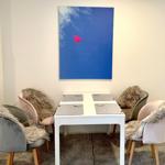 Esstisch mit vier Stühlen und Wandbild mit Herz.