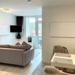 Wohn- und Essbereich mit Sofa, Fernseher und Tisch mit Stühlen.