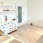 Wohnraum mit weißen Schränken, Holzboden und Tür mit Glas.