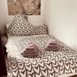 Schlafzimmer mit Bett, Herz-Muster-Bettwäsche und Wandbild.