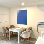 Essbereich mit weißem Tisch, vier Stühlen und Wandbild mit Herz. Hintergrund: weiße Wände und Decke.