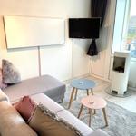 Ein Wohnzimmer mit Sofa, Fernseher und modernem Kaminofen. Durchgang zur Terrasse.