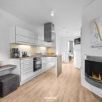 Küche mit Arbeitsfläche, Kühlschrank und Kaminofen mit brennendem Feuer.