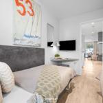 Zwei Betten, Wandbild, TV und Blick in Wohnbereich mit Balkon.