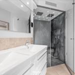 Badezimmer mit Dusche, Waschbecken und Spiegel