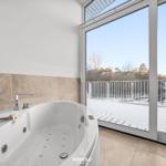 Eine Whirlpool-Badewanne mit Blick auf eine schneebedeckte Terrasse.
