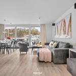 Wohn- und Essbereich mit Sofa, Tisch und Blick auf Balkon