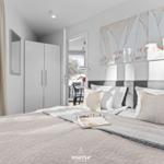 Schlafzimmer mit Bett, Wandbild und Blick auf Balkon.