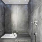 Duschkabine mit Steinwänden, Duschbrause und Lichtpunkten an der Decke.