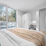 Schlafzimmer mit großem Fenster, Bett und Kleiderschrank. Draußen schneebedeckte Landschaft.