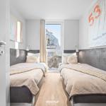 Zwei Betten mit Kopfteil, Wandbildern und Fenster mit Blick nach draußen.