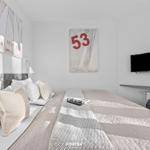 Schlafzimmer mit Bett, Wandbildern und Fernseher an der Wand.