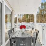 Terrasse mit Esstisch und Stühlen, weißer Zaun und Schnee im Hintergrund.