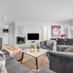 Wohn- und Essbereich mit Kamin, Sofa und Esstisch. Küche im Hintergrund.