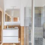 Bad mit Dusche, Waschbecken und Sauna. Fliesen und Holzoptik.