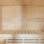 Holzsauna mit mehreren Sitzbänken und einer Holzdecke.