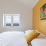 Schlafzimmer mit Bett, Fenster und Wandbild eines Eichhörnchens.