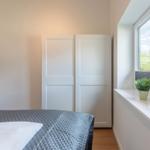 Schlafzimmer mit Bett, Kleiderschrank und Fenster mit Pflanze.