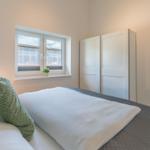 Schlafzimmer mit Bett, Fenster und Kleiderschrank.