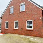 Holiday home with red brick facade and white windows. House number 5. Front yard with paving stones.