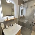 Bathroom with shower, sink, and lit mirror.