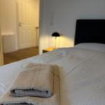 A bed with folded towels and a bedside lamp in the background.