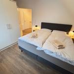 Bedroom with double bed, two nightstands, and wardrobe. Wooden floor and lamps.