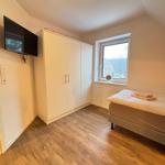 Bedroom with bed, wardrobe, and wall-mounted TV. Wooden floor and window with view.