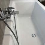 A white bathtub with chrome faucet and handheld shower.