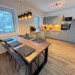 Dining area with table and chairs. Kitchen with worktop and appliances.